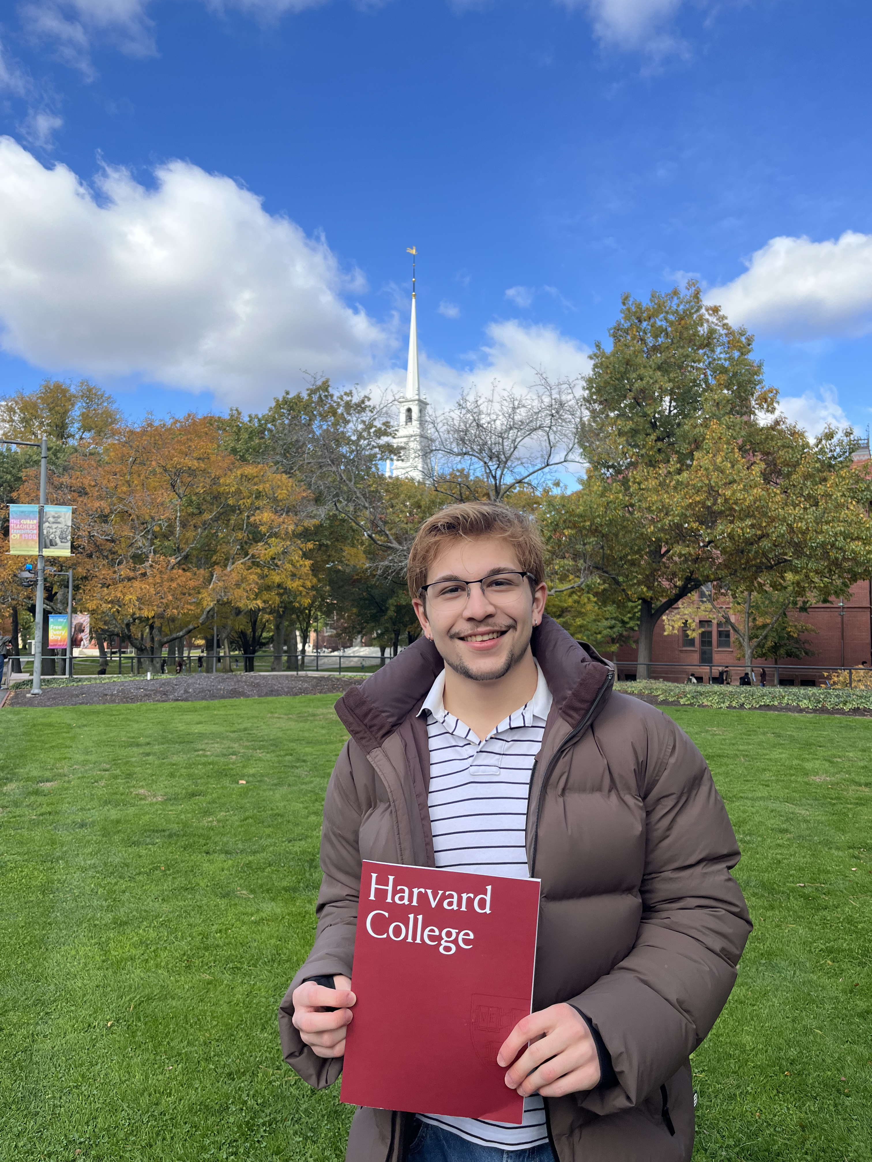 João Lucas Oliveira Silva holding a Harvard College folder in Harvard Yard